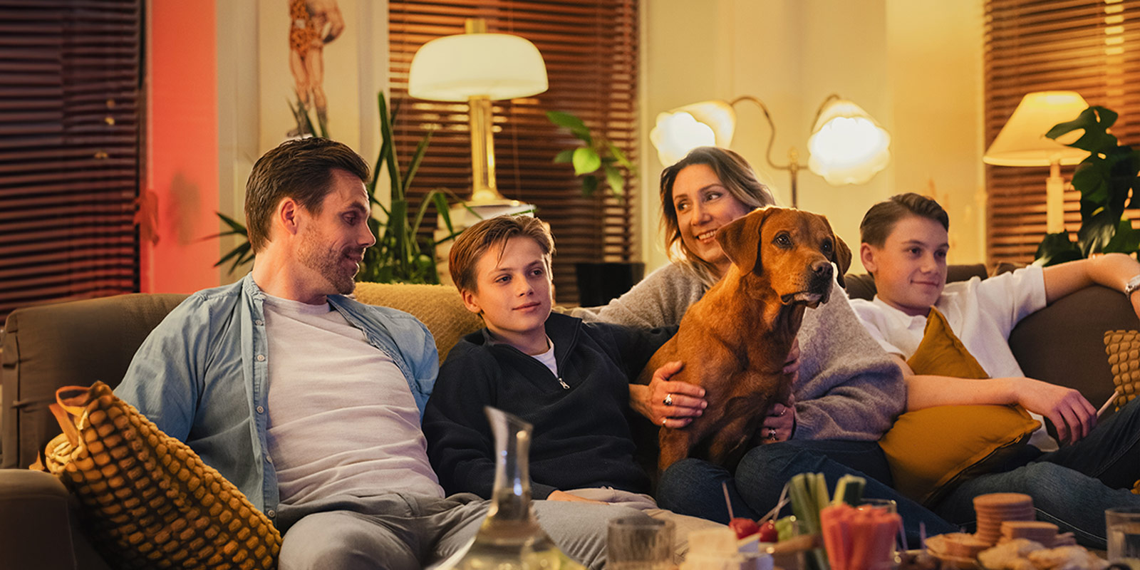 Familj med barn och hund sitter i soffan